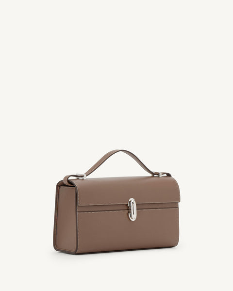 Brown handbag with top handle with a silver clasp on a light beige background