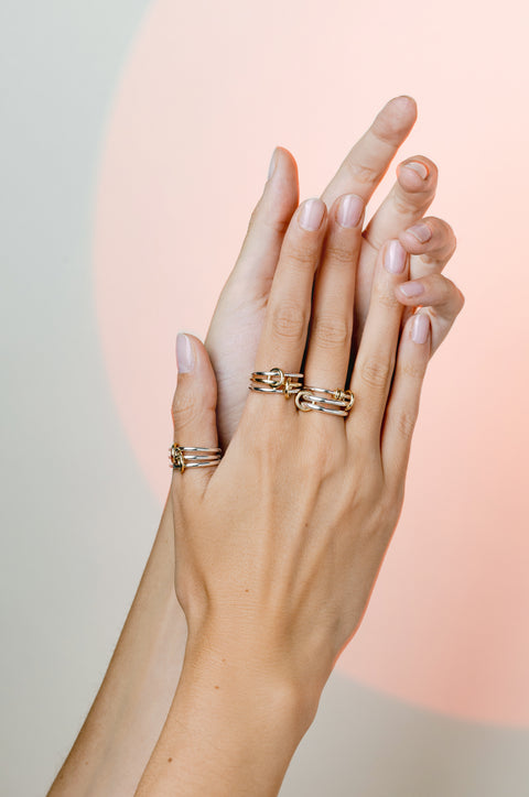 A woman wearing two Spinelli Kilcollin Solarium rings, one all sterling silver bands and one two sterling silver bands and one yellow gold band. Also wearing on Raneth SG ring.