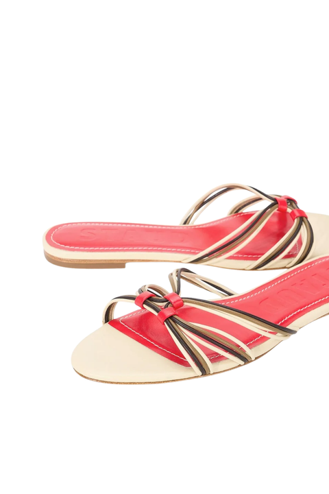 A pair of women's slide sandals featuring a vibrant red insole, decorated with thin, multi-colored woven straps in red, beige, and black, set against a plain white background.