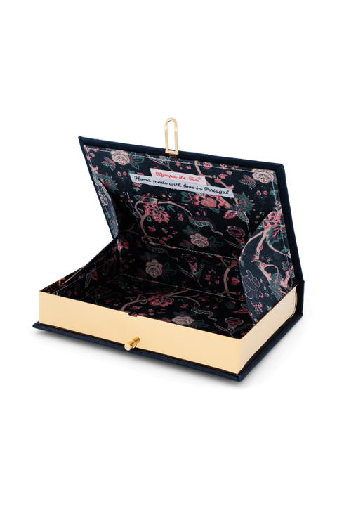 A book clutch with a black floral velvet interior and a gold-tone metal clasp, shown open on a white background.