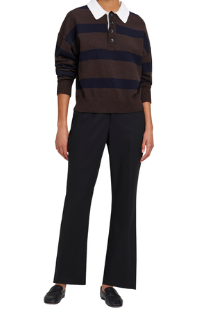 A model wearing a brown and navy striped knit polo sweater with a white collar, paired with black wide-leg trousers and black loafers, on a solid white background.
