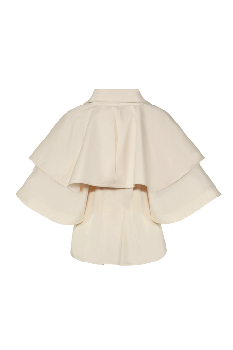 An off-white-colored structured cape jacket with layered ruffles and wide flared sleeves, shown against a plain white background.