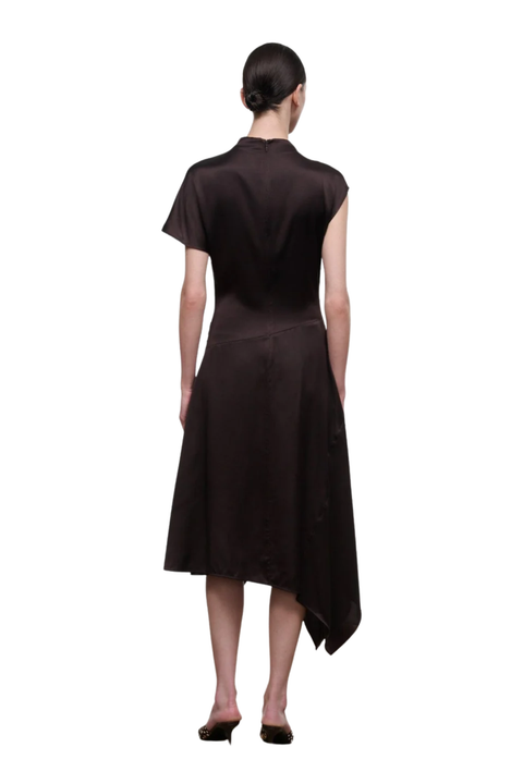 A woman viewed from the back wearing a dark brown short-sleeve midi dress with an asymmetrical hem, paired with black heels, against a plain white background.