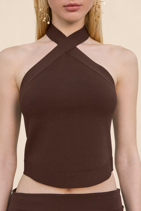Close up of a woman wearing a brown knit tank top that features a halter neck, paired with a brown maxi skirt.