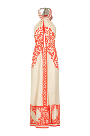 A cream-colored halter maxi dress with vibrant red-orange printed patterns, shown on a white background.