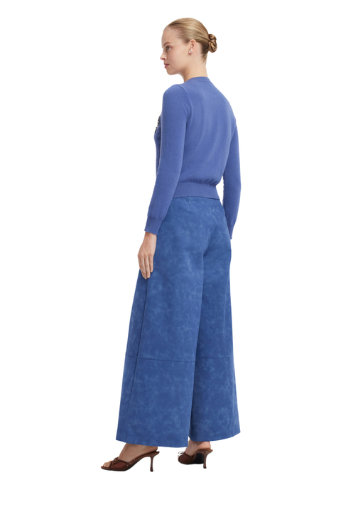 A woman shown from the back wearing a blue long-sleeve knit top and matching wide-leg blue trousers, paired with dark brown heeled sandals, against a plain white background.