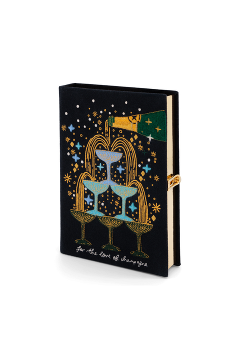 A black book clutch featuring a colorful tarot card illustration of the Three of Cups, complete with gold cups, stars, and a flag, with the title 'The Three of Cups' printed in white script at the bottom.