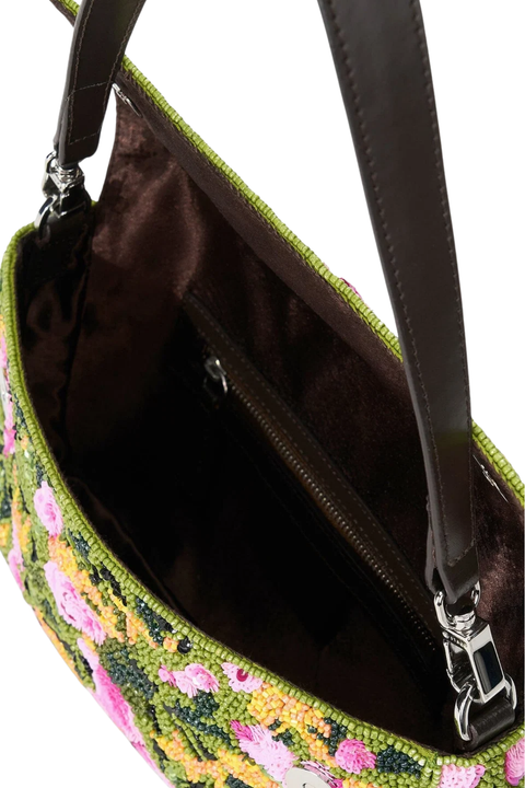 Close-up of a handbag interior showing a dark brown satin-lined compartment with a zipper, a green floral embroidered exterior, and a dark brown strap with silver hardware on a white background.