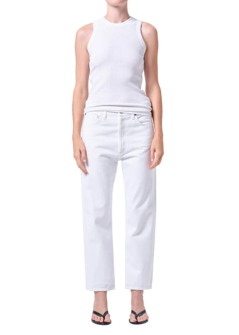 Person wearing a white sleeveless top and high-rise, straight leg, white jeans on a plain background from the front