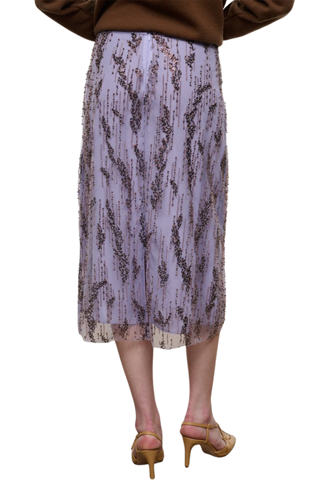 A lavender embellished midi skirt with a brown abstract pattern, shown on a model from the back wearing tan high-heeled sandals against a white background.