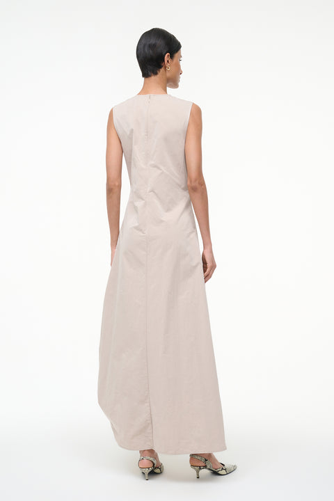 Back-facing woman wearing a beige sleeveless asymmetrical dress