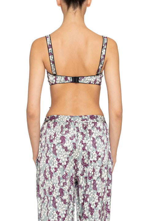 Back-facing woman wearing a floral patterned underwire bra top and pants on a plain background.
