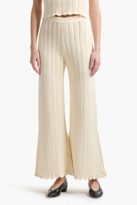 Up close of cream knitted pants on woman wearing black shoes.