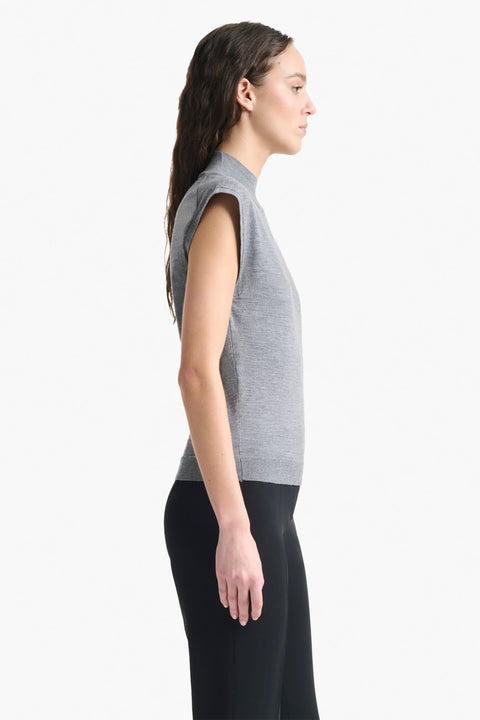 Woman facing the right showing side of grey cap sleeve sweater top.
