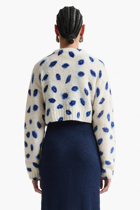 Woman facing the back in cropped sweater with blue kiss print.