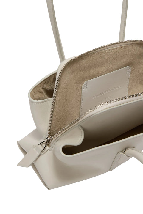 Up close of inside of white handbag with a visible brand label on a light gray background