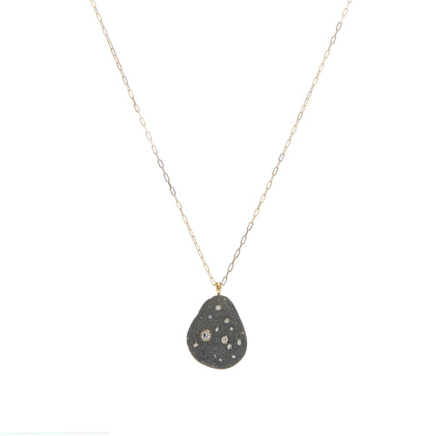 A triangular black and white stone embellished with a larger diamond and three smaller diamonds, suspended on a yellow gold paperclip chain.