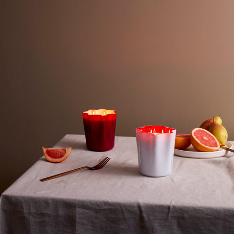White and red murano glass candles lit on a tablescape.