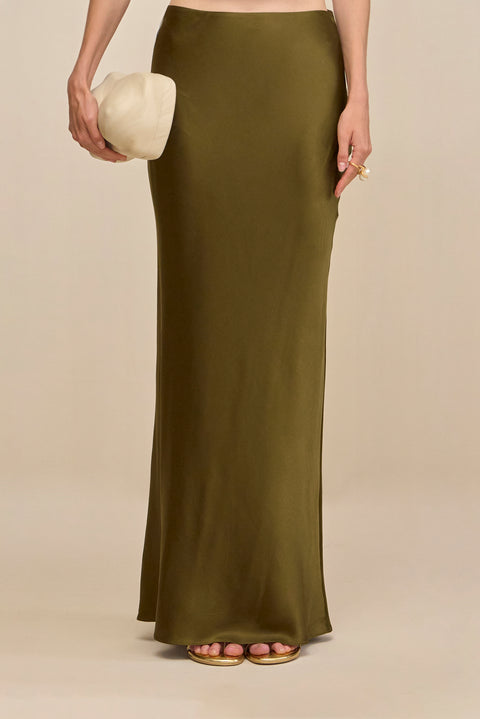 Close up of a woman wearing an olive green silk maxi skirt.