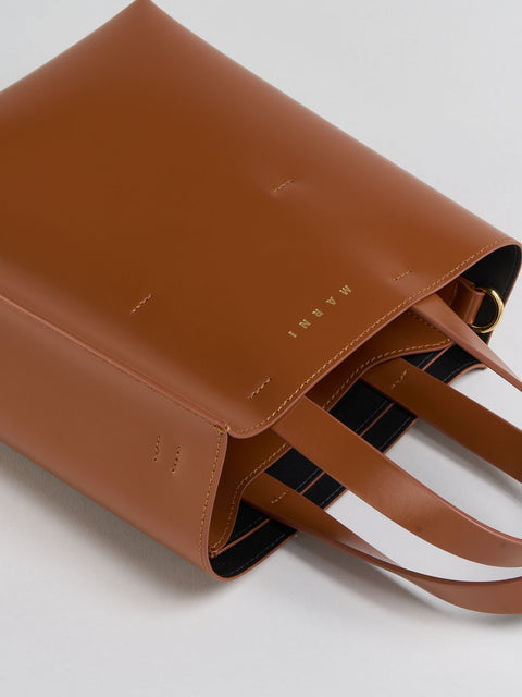 Brown leather handbag with visible brand name on a light gray background