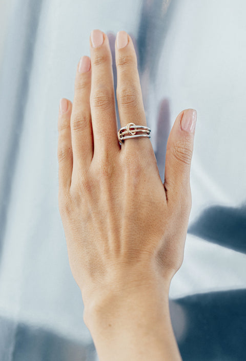 Woman wearing a Spinelli Kilcollin Solarium ring that features two 1.7mm sterling silver bands and one 1.7mm 18k yellow gold band connected by two 18k yellow gold connectors.