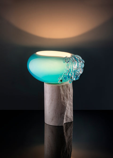 Light inside of blue glass piece on top of marble stand.