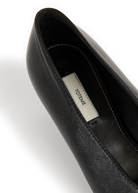 Close-up of a black leather shoe interior showing a white insole label with the brand name TOTEME.
