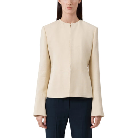 Woman wearing a beige blazer and dark pants on a light background