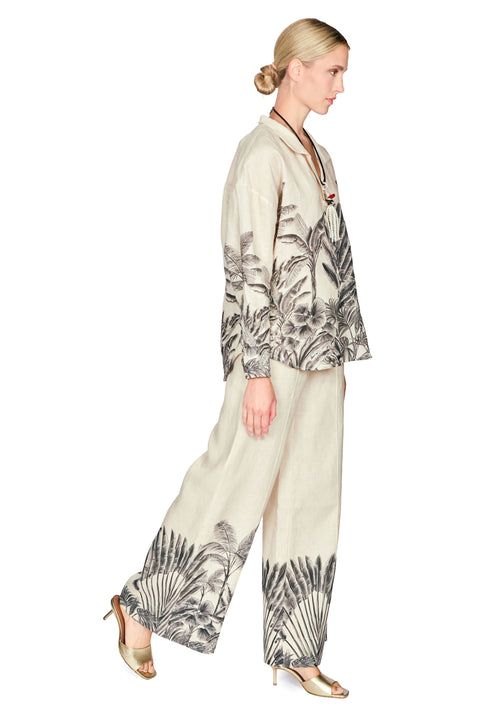 Woman wearing a patterned button down blouse and long pants on a white background side angle