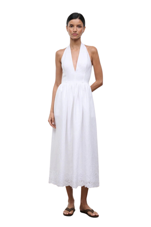 Woman wearing a long white halter neck dress on a white background