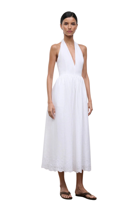 Woman wearing a long white halter neck dress on a white background side