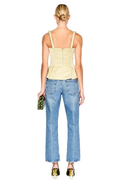 A woman shown from the back wearing a pale green peplum camisole top and light blue wide-leg jeans, holding a small green clutch against a plain white background.