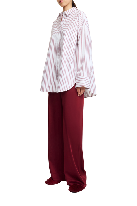 Person wearing a white and red striped shirt with burgundy pants on a white background