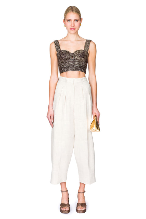 Woman wearing a black and tan woven bustier crop top and white pants on a white background