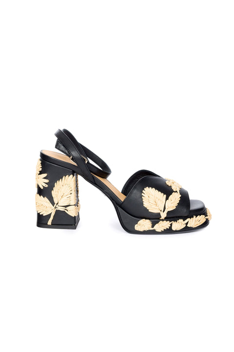 Black platform sandal with woven leaf patterns on a white background.