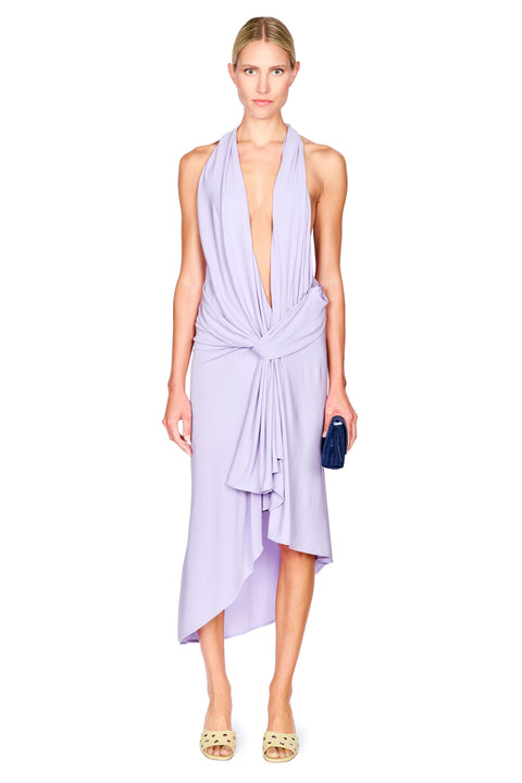 A woman wearing a purple halter midi dress with a low cut, draped neckline and waist