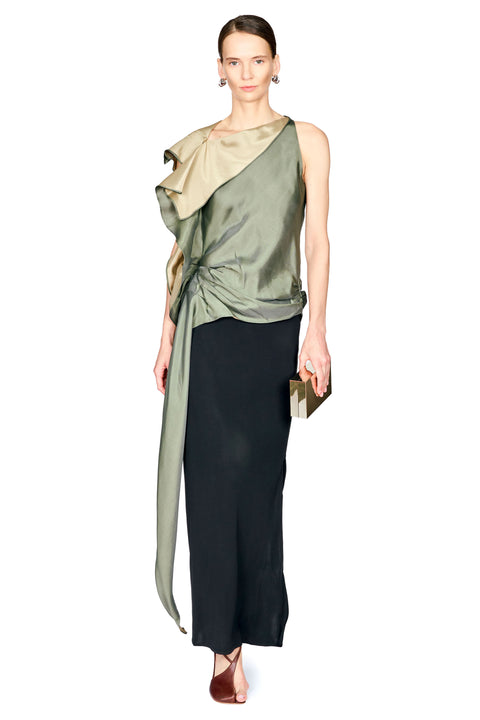 A model wearing a sleeveless, one-shoulder draped top with a metallic olive green folded collar and a long black skirt, holding a small black clutch against a plain white background.