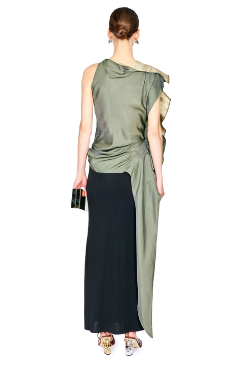 A woman shown from the back wearing a sleeveless draped top with an olive green upper section and a long black skirt, holding a small black clutch against a plain white background.