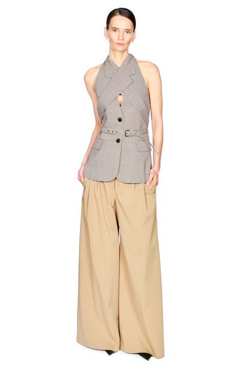 A model wearing a sleeveless gray pinstriped wrap-style blazer with a belt and beige wide-leg trousers, photographed against a plain white background.