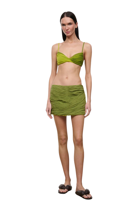 Woman wearing a green mini skirt cover up set on a white background