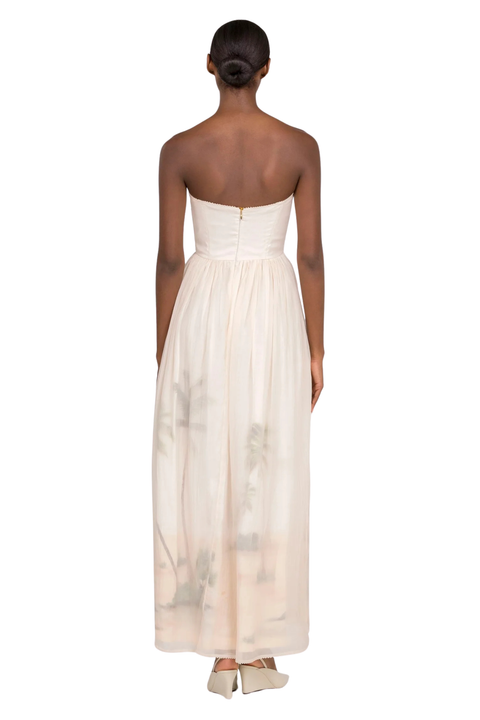 A woman wearing a cream strapless maxi gown with a sweetheart neckline with a zipper closure on a white background