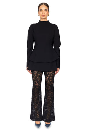 Woman wears long sleeve black curved hem top with black lace pants.