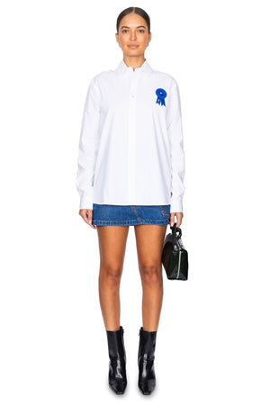 Model styled in the white button down shirt with blue ribbon applique.