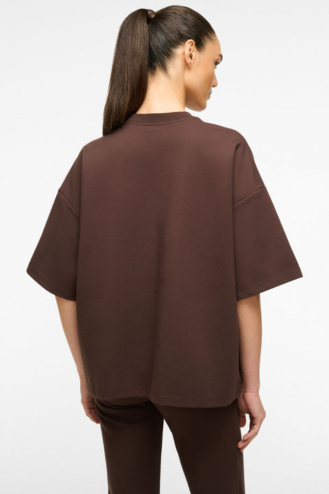 Back view of a woman wearing an oversized brown t-shirt with matching brown pants. 