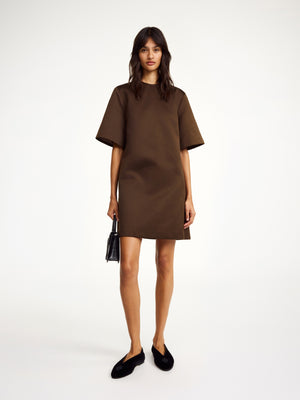 Woman wears brown satin mini dress with short sleeves.