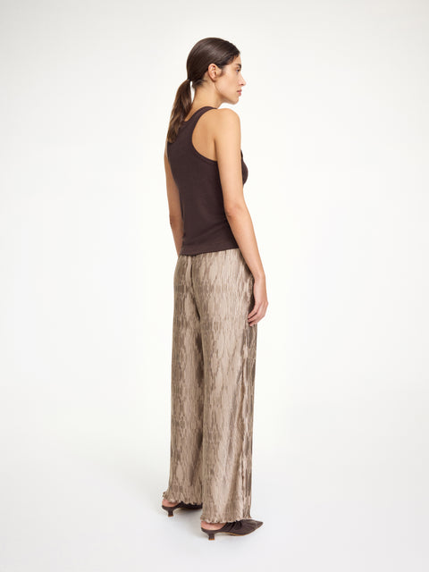 Back-facing woman wearing light brown textured pants with a dark brown tank top. 