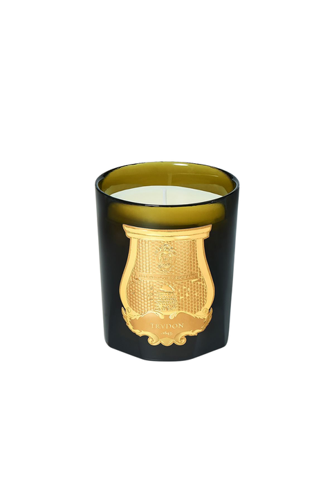 An olive green murano class candle vessel with a gold crest logo with white wax on a white background. 