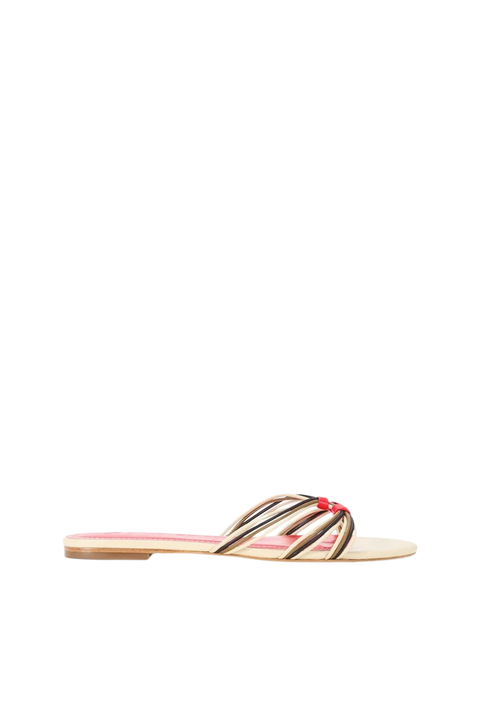 A single flat slide sandal shown in profile against a solid white background. The sandal features a light beige footbed, a red inner lining, and metallic gold-toned straps with a small red accent at the center.