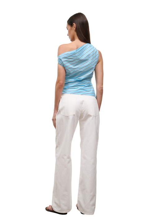 A woman shown from the back wearing a light blue and white striped one-shoulder top and white pants against a plain white background.