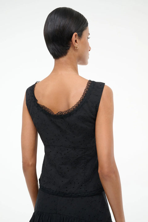 Back view of a woman wearing a black eyelet tank top with lace trim, paired with a matching skirt. 